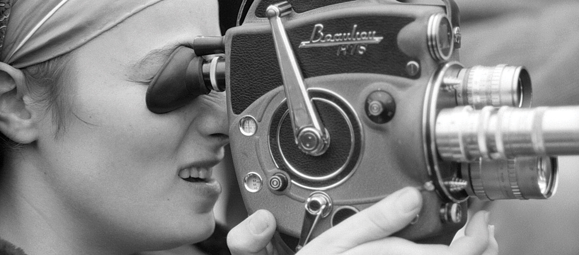 A black and white profile photo of 1960s experimental filmmaker Barbara Rubin looking through a movie camera viewfinder; promotional image for Chuck Smith's 2018 documentary Barbara Rubin & the Exploding NY Underground