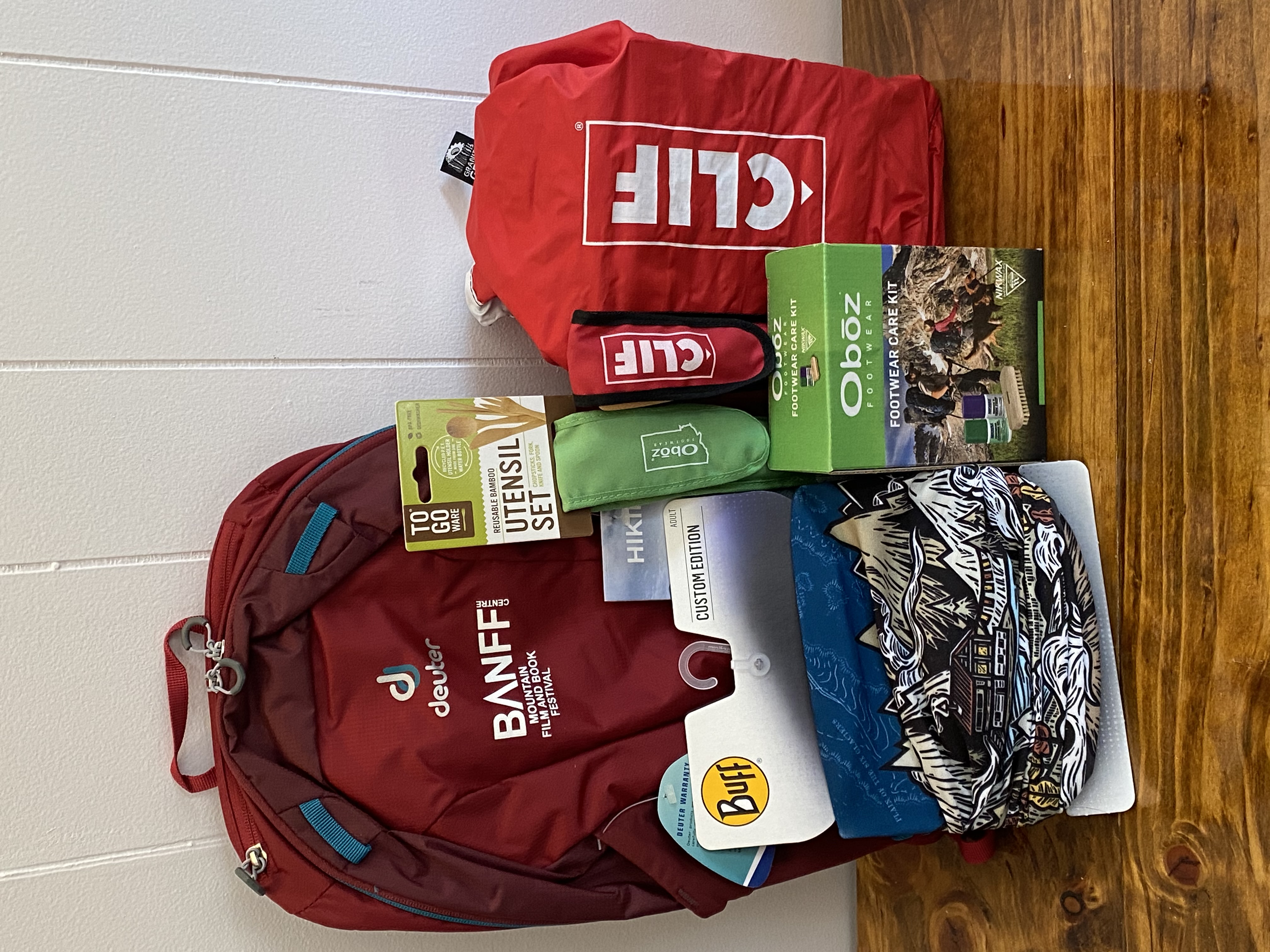 A photo of the items available in the Banff prize package, including a red backpack, red tote bag, a face mask, and green package containing a utensils kit
