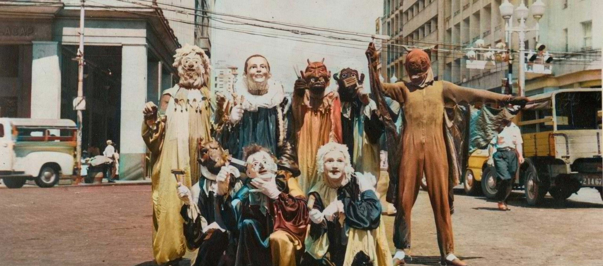 An old color photograph of a group of people in costume, all wearing different masks.