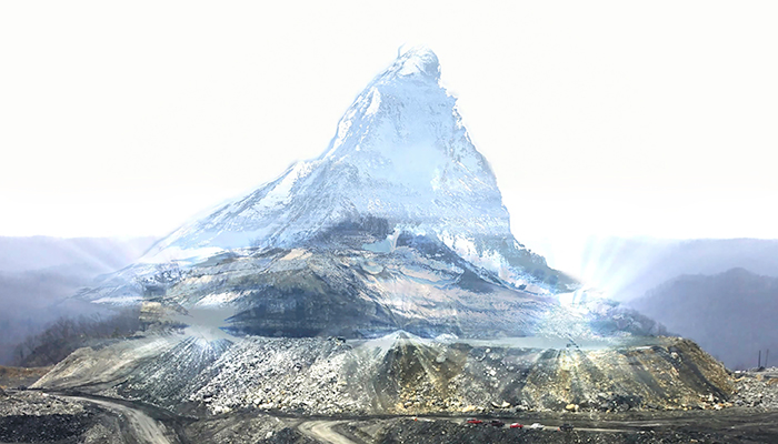 Image of a barren mountain with road cuts and a partially flattened top. A holographic projection of a snowy mountain peak is superimposed over it. 