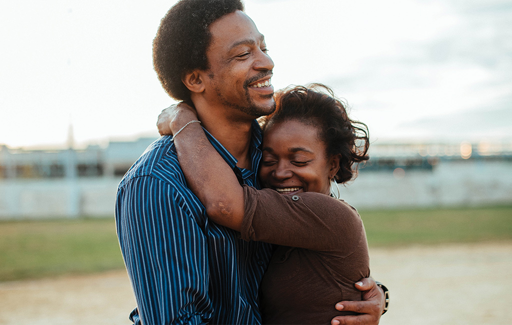 African American couple Christopher and Christine Rainey stand outside holding each other and smiling in a scene from Jonathan Olshefski and Lindsay Utz's documentary Quest