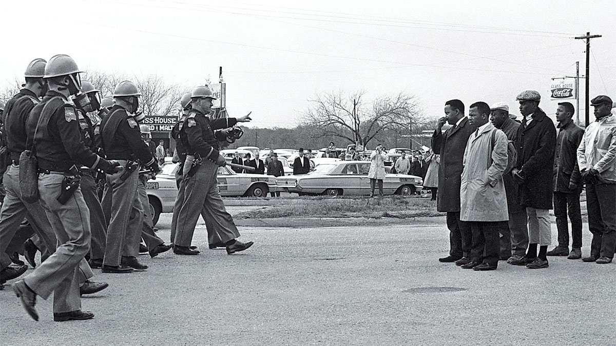 a black and white photo of police on the left and african american protestors on the right with the press behind them
