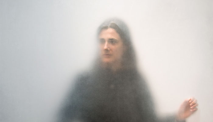 Photo portrait of dance artist Faye Driscoll as seen behind a diffusing scrim against a neutral gray background; image taken as part of artist Ann Hamilton's "One Everyone" project