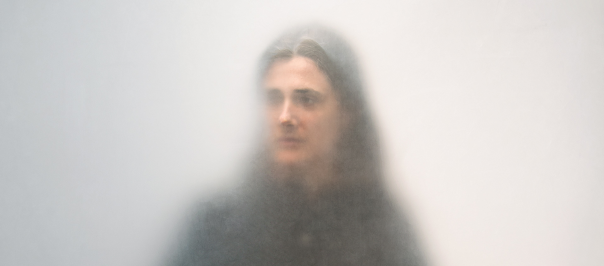 Photo portrait of dance artist Faye Driscoll as seen behind a diffusing scrim against a neutral gray background; image taken as part of artist Ann Hamilton's "One Everyone" project