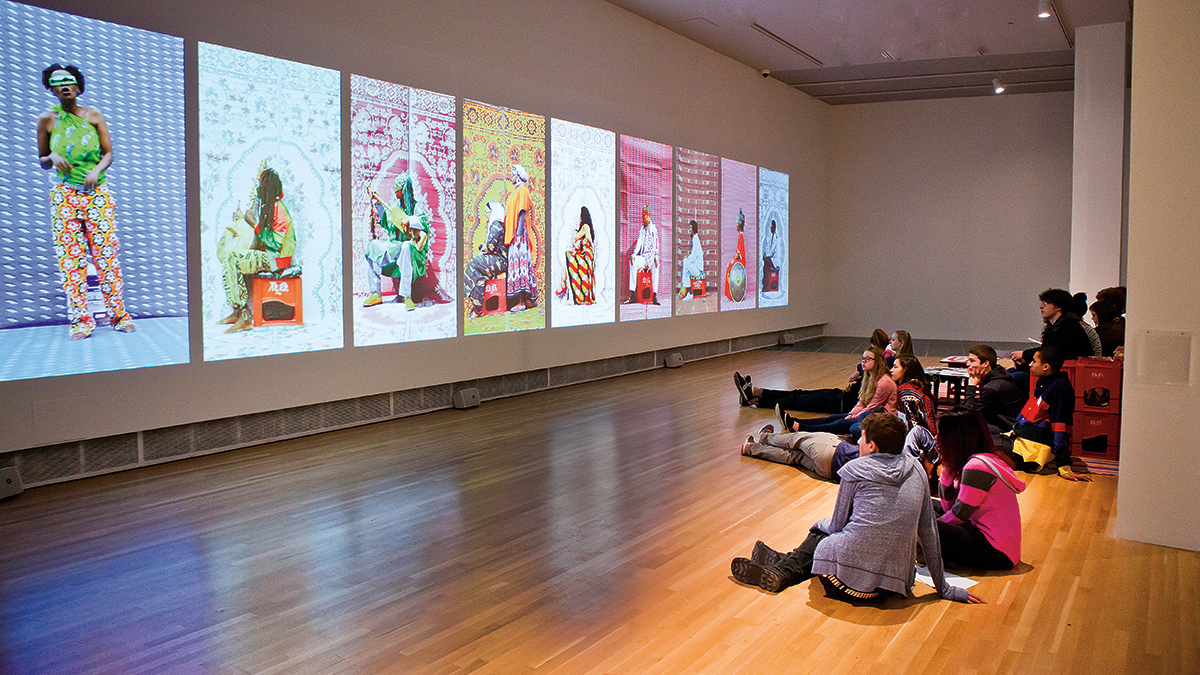 Patrons watching the three-channel video of music performers in the Wexner Center galleries