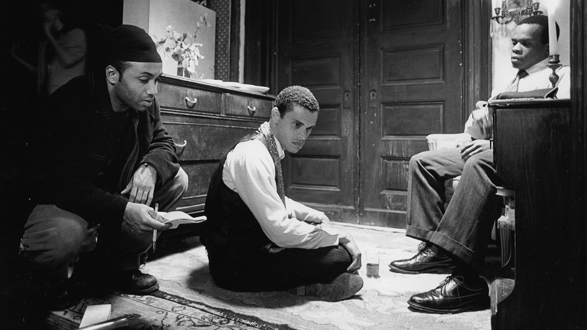 Three men sitting around in a room talking.