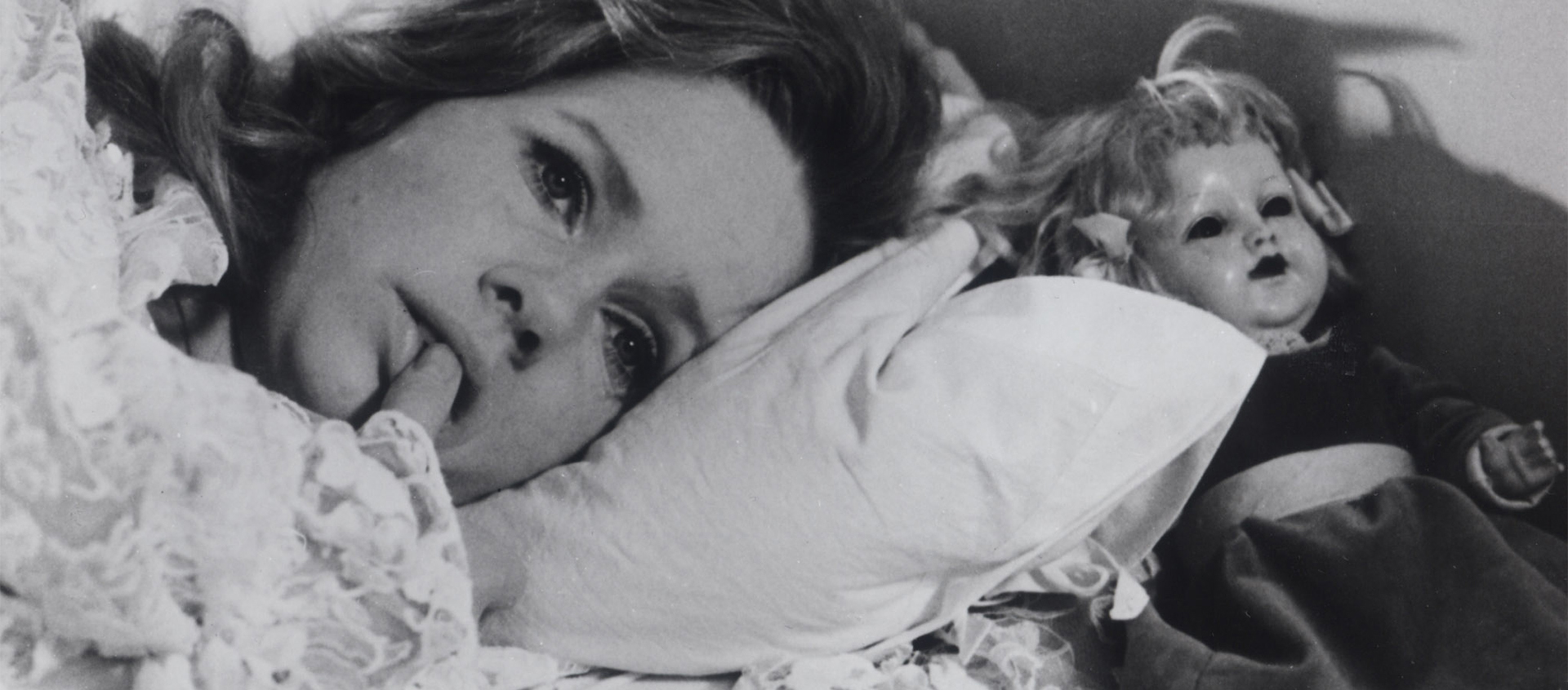 Black and white movie still of a woman laying in bed.