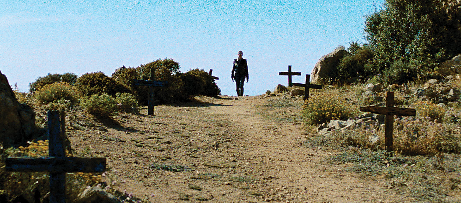 Man walking through path lined with crosses