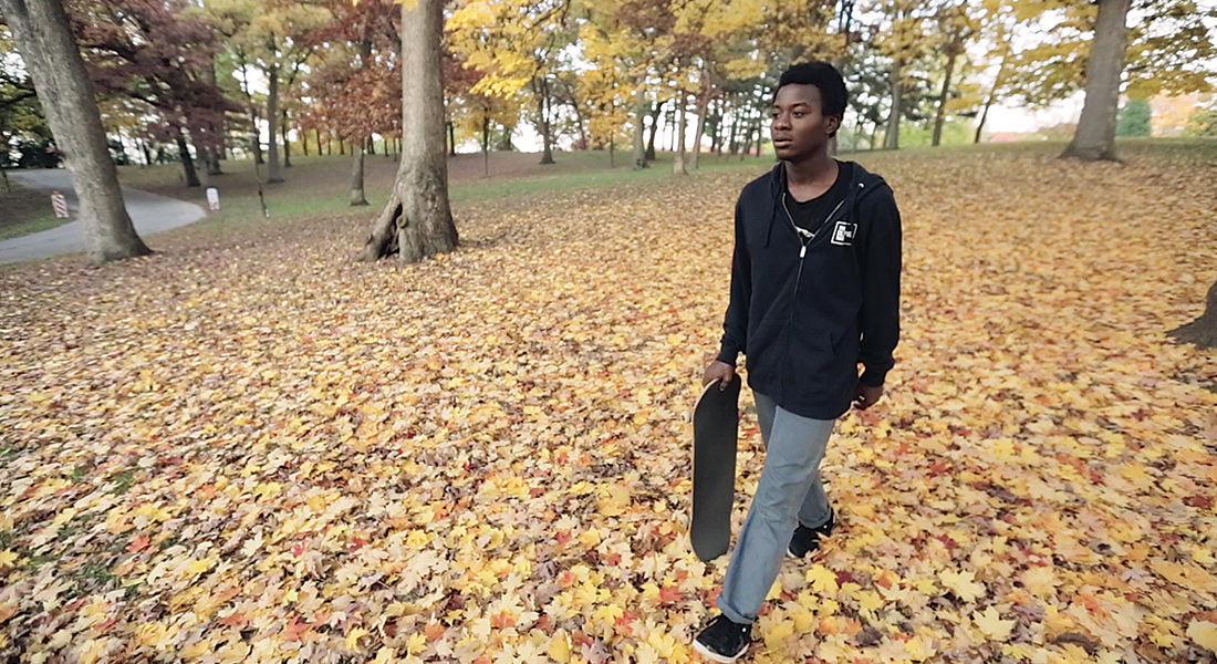A boy walks across fallen leaves