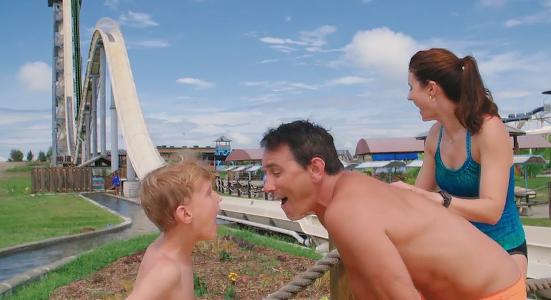 (right to left) son, father, and mother in front of a waterslide