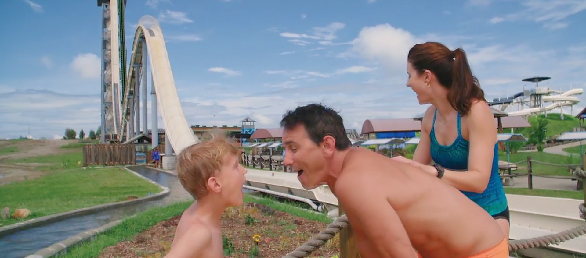 (right to left) son, father, and mother in front of a waterslide