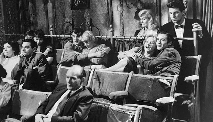 black and white picture of people watching a movie in an decrepit theater, from the 1958 Basil Dearden film The Smallest Show on Earth 