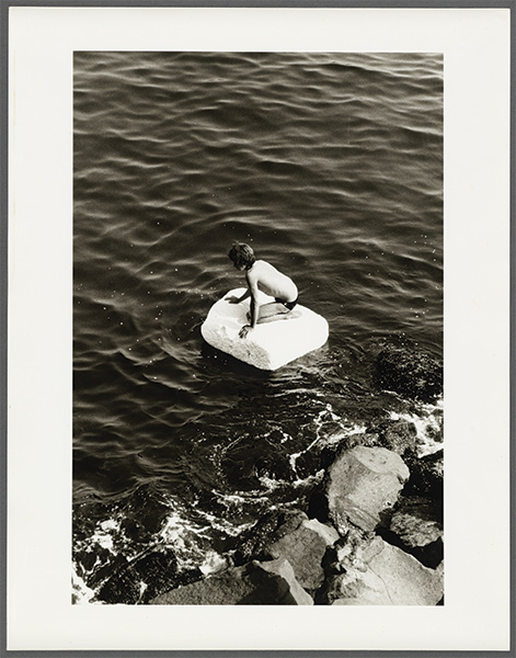 A boy floats on a small raft in the water