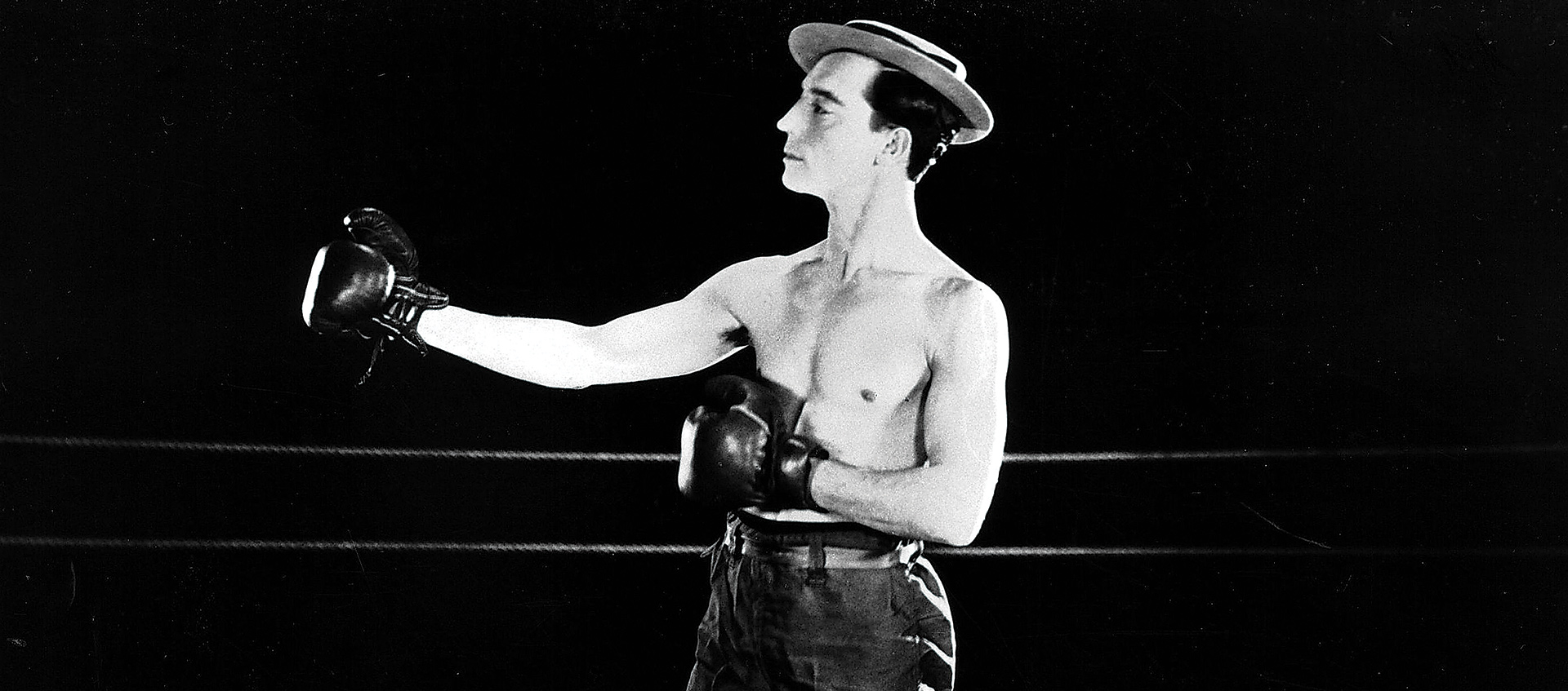 Man in hat poses with boxing gloves in a fighting stance