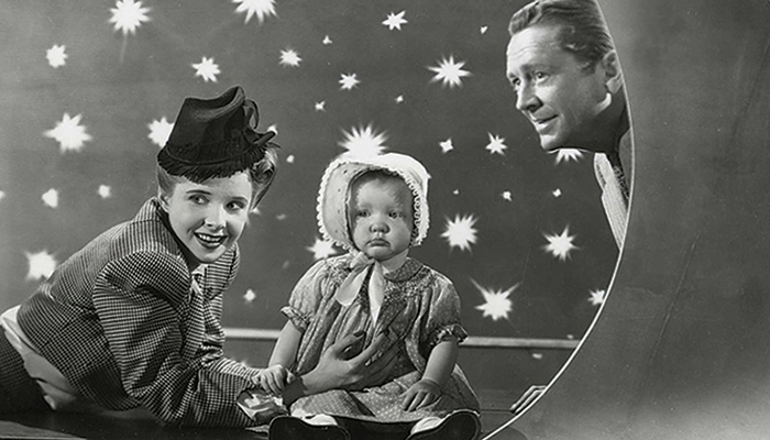 A family of three poses in a photo studio decorated with a moon and stars
