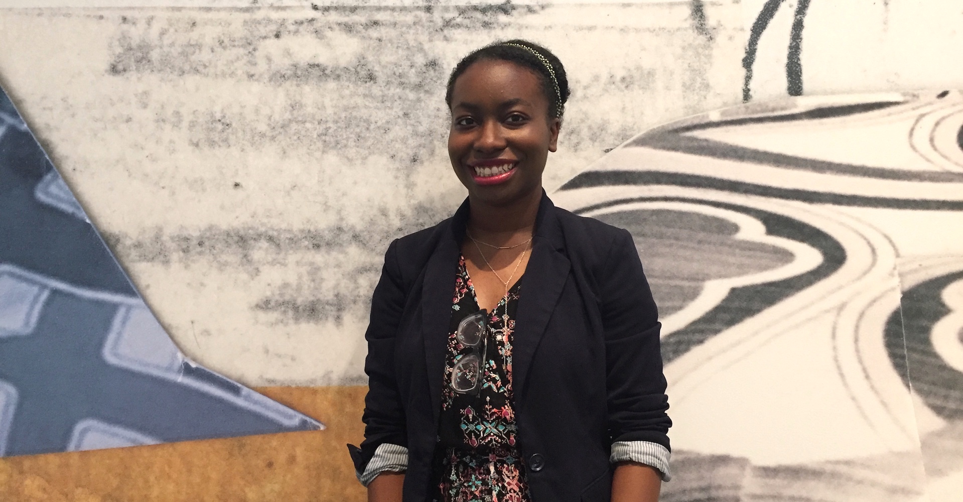 Ebony Bailey, an intern at the Wexner Center for the Arts at The Ohio State University for the 2018-19 school year, standing in front of a wall mural by artist Mickalene Thomas