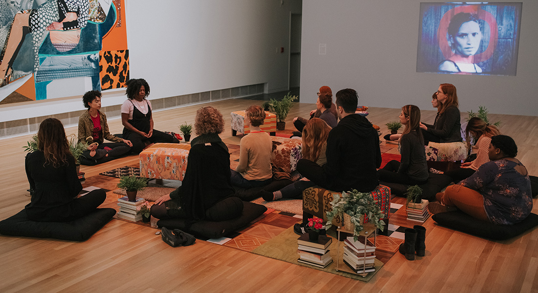 A group of people meditate in a gallery.