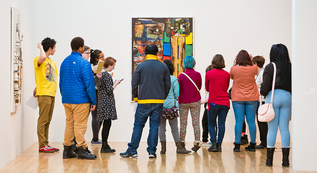 A group of people tour a gallery. 