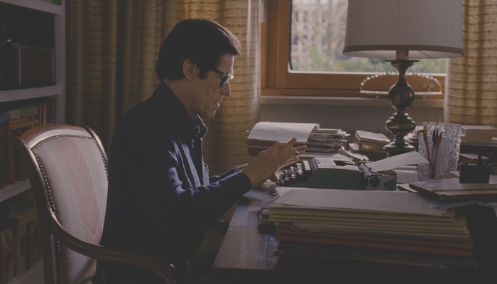 Willem Dafoe as filmmaker Pier Paolo Pasolini sits at a desk and types in a still from Abel Ferrar's biopic Pasolini, courtesy of Kino Lorber Films 