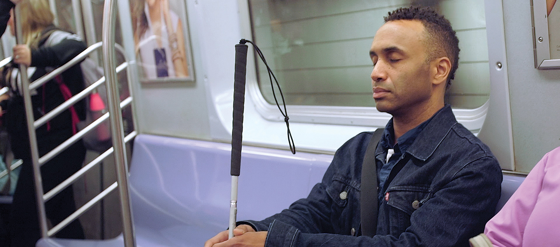 Man holding cane, sitting on train