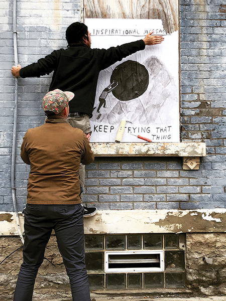 Artist Nathaniel Russell installs his work with help