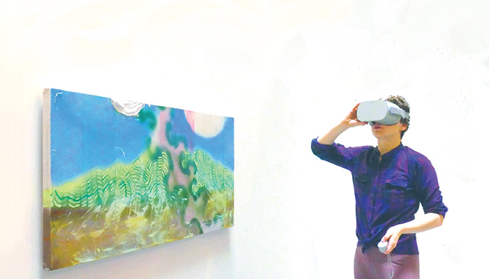 Person wearing virtual reality goggles next to colorful painting