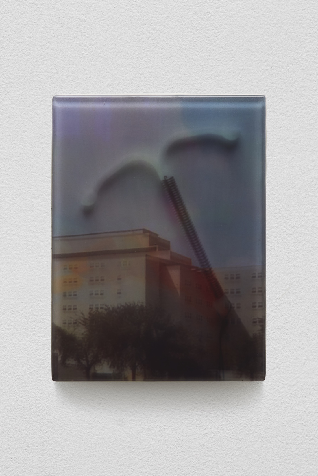 a photograph of a building with trees is collaged with an image of an IUD in a segment from Sadie Benning's installation Pain Thing