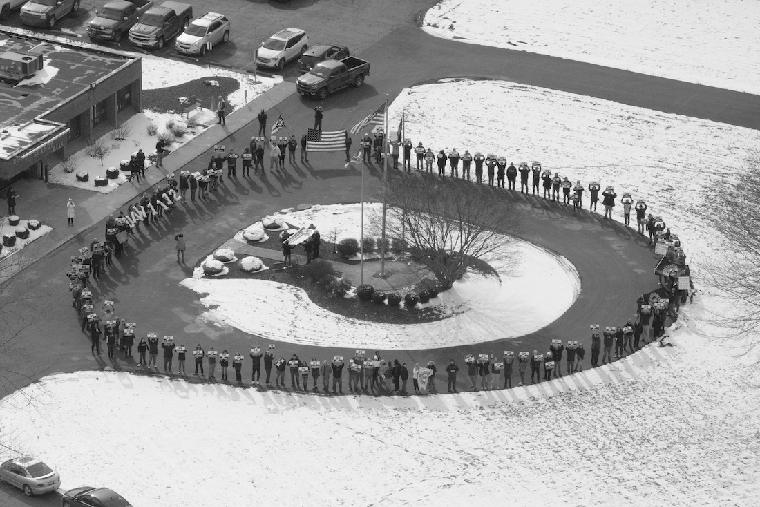 An overhead shot of GM employees forming a circle of protest in front of the Chevy Cruze plant in Lordstown, Ohio in a black and white photograph shot by LaToya Ruby Frazier