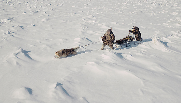 Two figures cross a snow-covered landscape with a dogsled in a scene from the Bulgarian film Aga