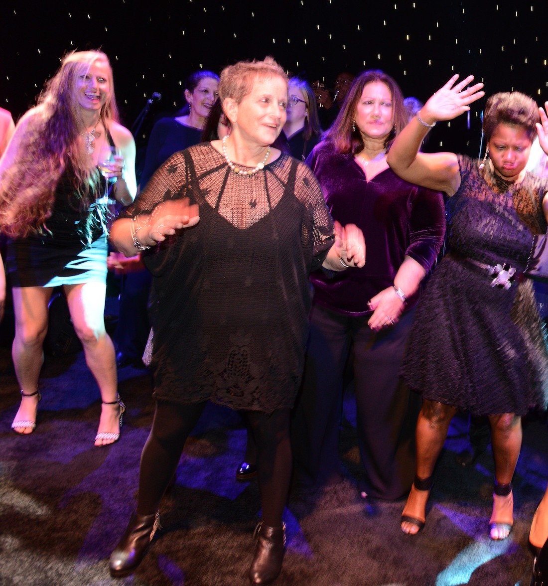 Wexner Center supporter Janice Roth dances with other guests against a dark background during the 2018 Anniversary Party at the Wexner Center for the Arts