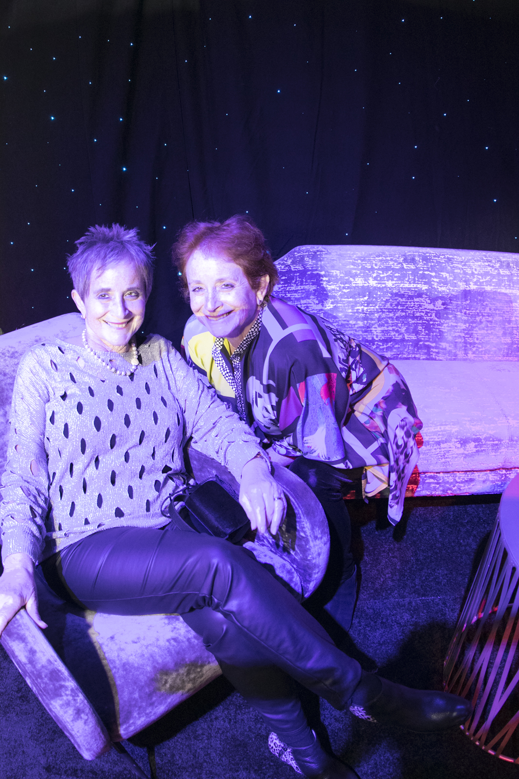 Wexner Center supporters and sisters Janice Roth and Joyce Shenk sit together against a light-flecked background during the 2018 Anniversary Party at the Wexner Center for the Arts