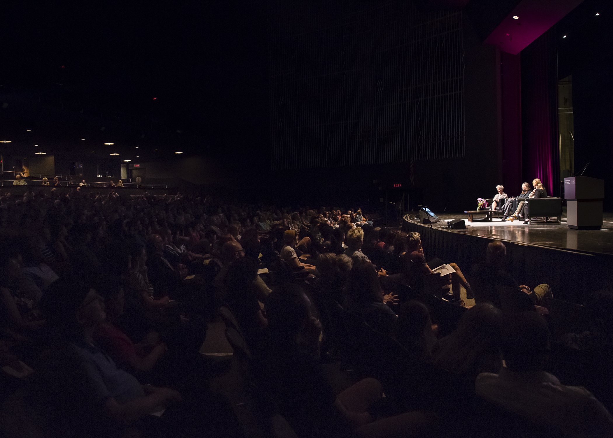 A wide shot of the audience watching the September 2019 talk between HERE artists Ann Hamilton, Jenny Holzer, and Maya Lin with Wexner Center for the Arts Director Johanna Burton on the stage of Mershon Auditorium