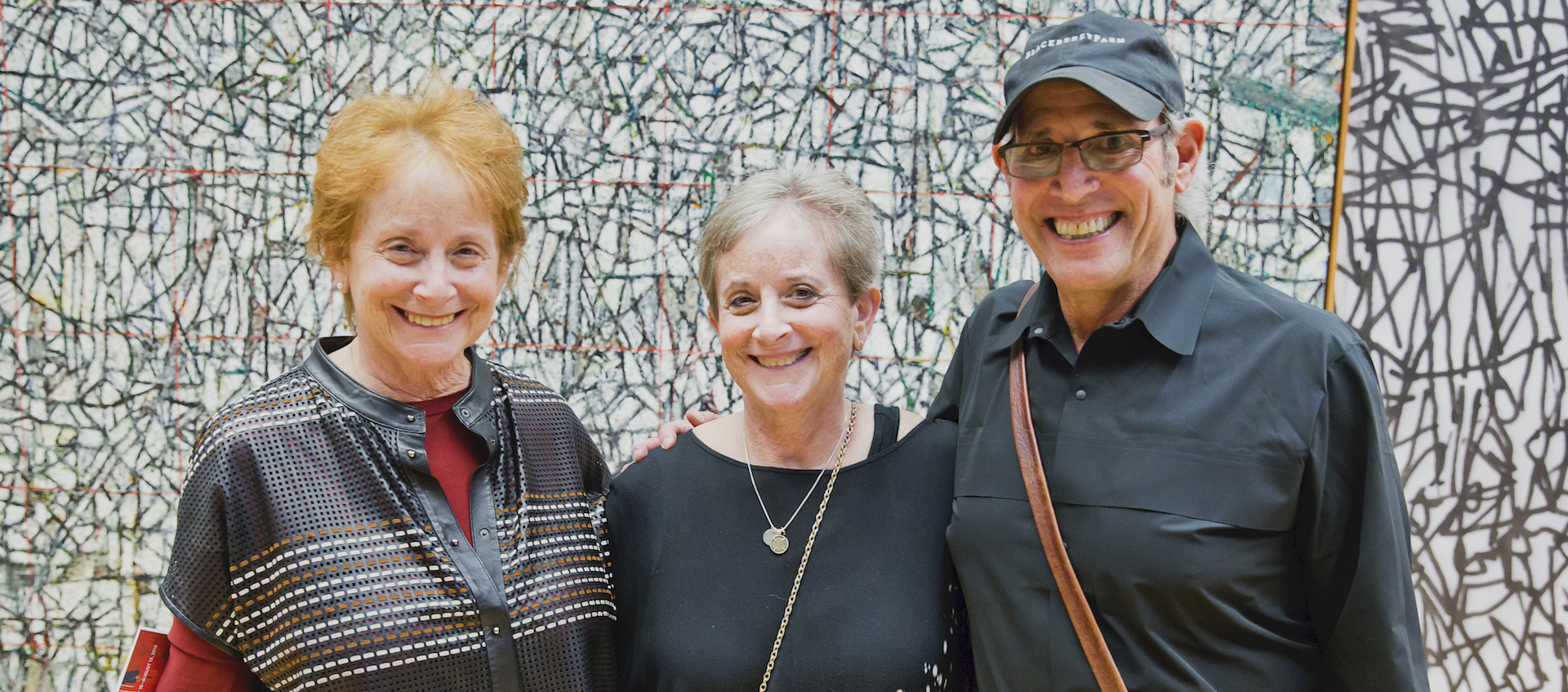 Sisters Joyce Shenk and Janice Roth stand with Shenk's husband Chuck in front of a mural by artist Zachary Armstrong for the spring 2018 exhibition Inherent Structure at the Wexner Center for the Arts at The Ohio State University. Photo by Katie Spengler Gentry