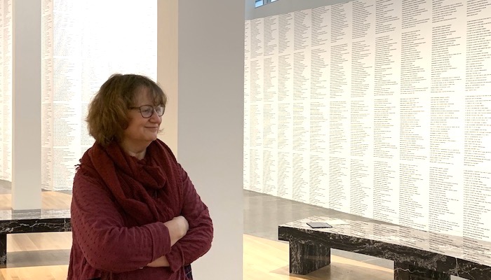 Ohio State professor of English Elizabeth Weiser stands with her arms folded in a gallery covered floor to ceiling with text by artist Jenny Holzer during a gallery talk at the Wexner Center for the Arts