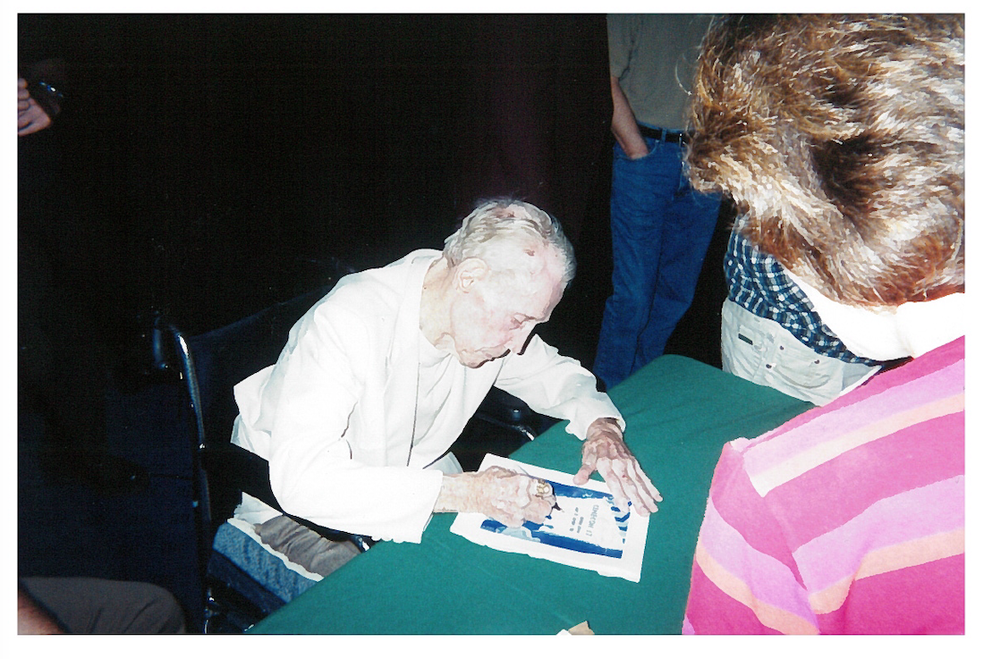 Filmmaker Budd Boetticher sits at a table autographing memorabilia during a September 2001 appearance at the Egyptian Theatre during Cinecon Los Angeles