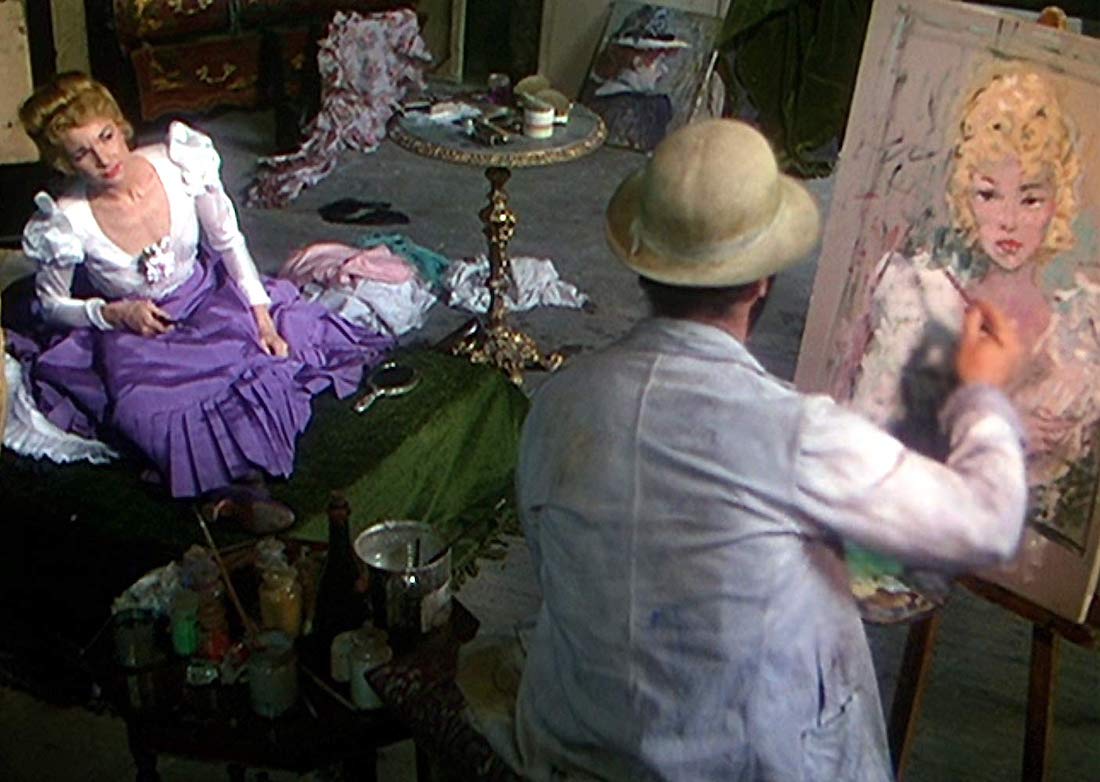 A female model in white blouse and purple skirt sits and looks at the portrait of her being painted by an artist in straw hat and white coat with his back to the camera in a scene from John Huston's 1952 film Moulin Rouge