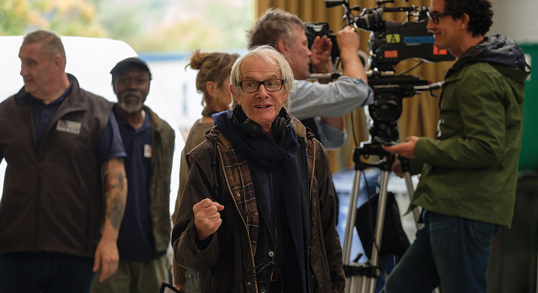 Director Ken Loach at work on the set of Sorry We Missed You with camera operators and extras behind him.