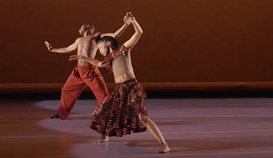 Two African American dancers are caught in a moment of dancing in unison in a performance by Alvin Ailey Dance Theater