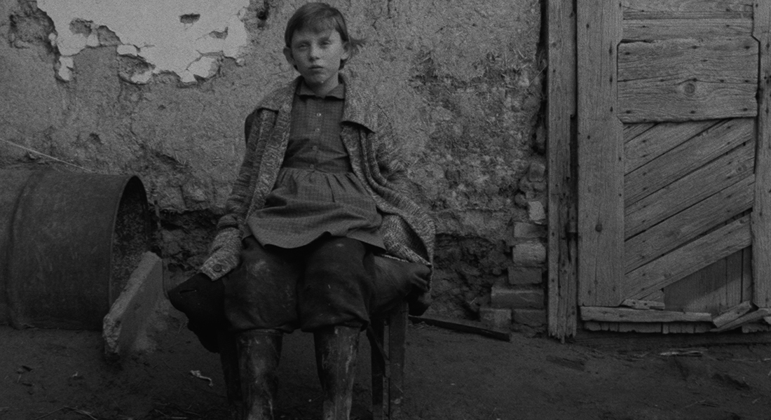 a child sitting on a stool in front of a house