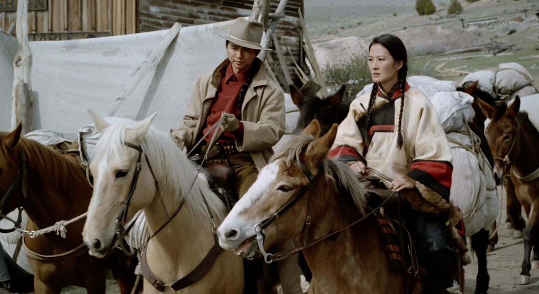 a man and woman with luggage mounted on several horses