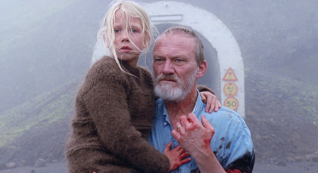 a grieving man (Ingvar Sigurðsson) carries his daughter on his waist in front of tunnel entrance