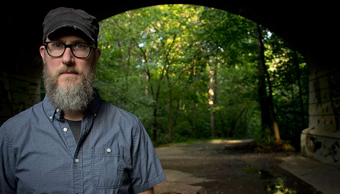 Brian Harnetty in cap and glasses in front of a tunnel entrance