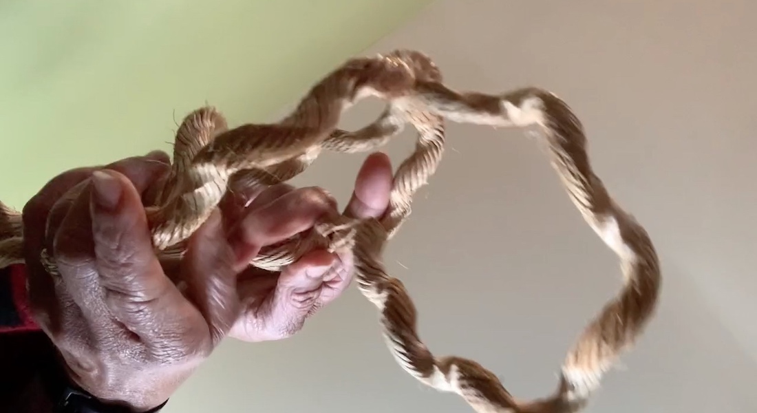 The hands of dancer and choreographer Bebe Miller holding a thick, loose piece of rope