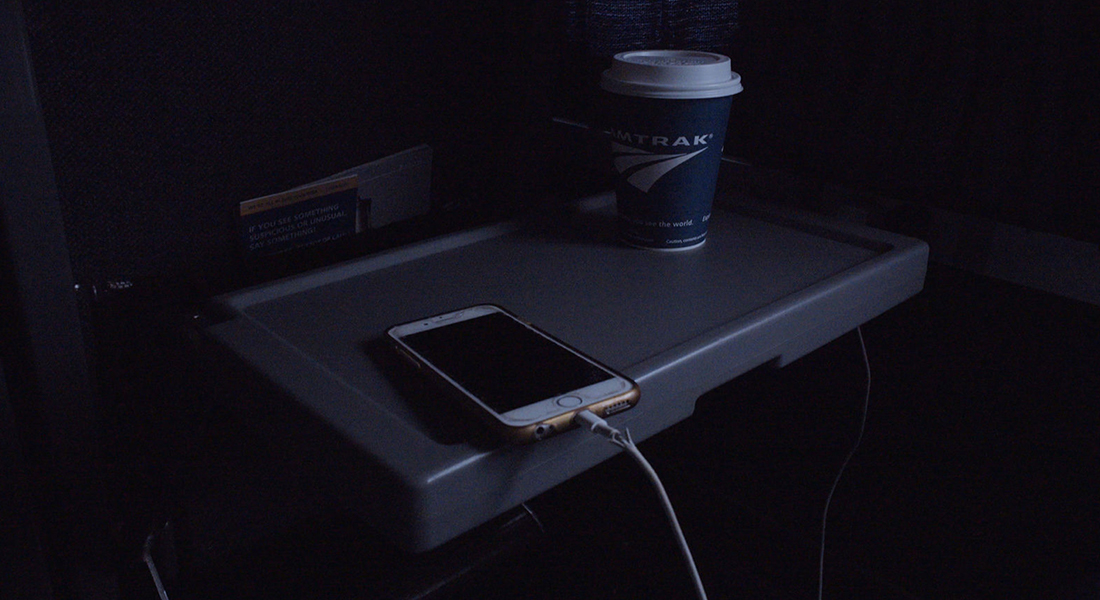 a phone and a hot drink cup on a seat tray