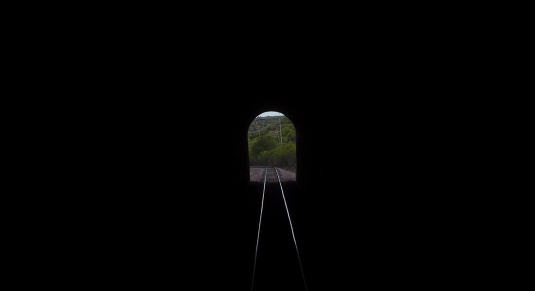 train tracks leading out from a dark tunnel