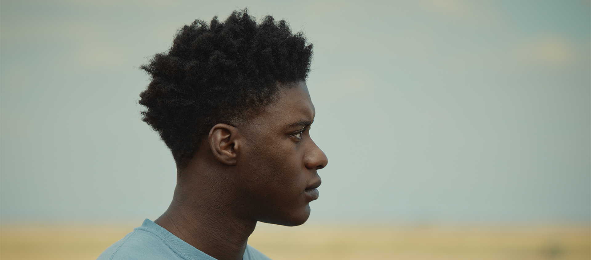 A teenaged Femi, shown in profile, looks off into the distance