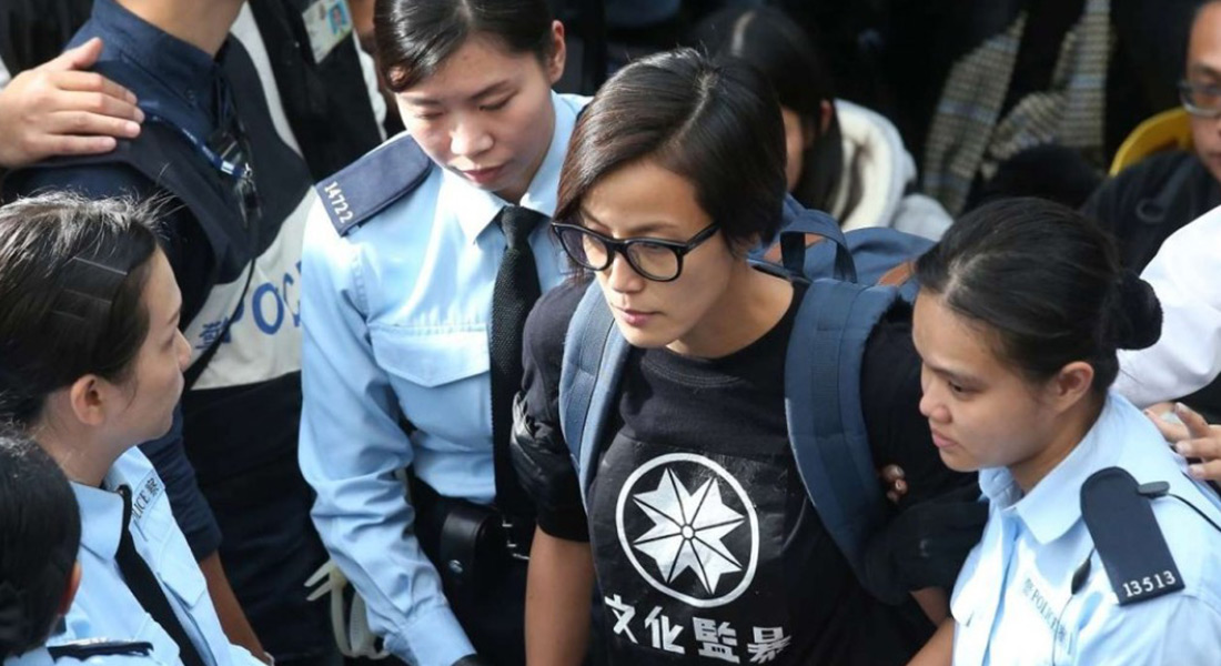 Denise Ho in plain clothes is escorted by Hong Kong police