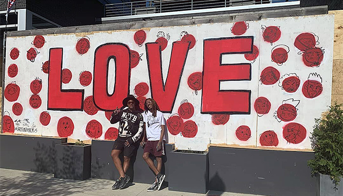 Columbus artists Bryan Moss and Hakim Callwood stand in front of a "Love" mural on the front of Donato's in the Short North