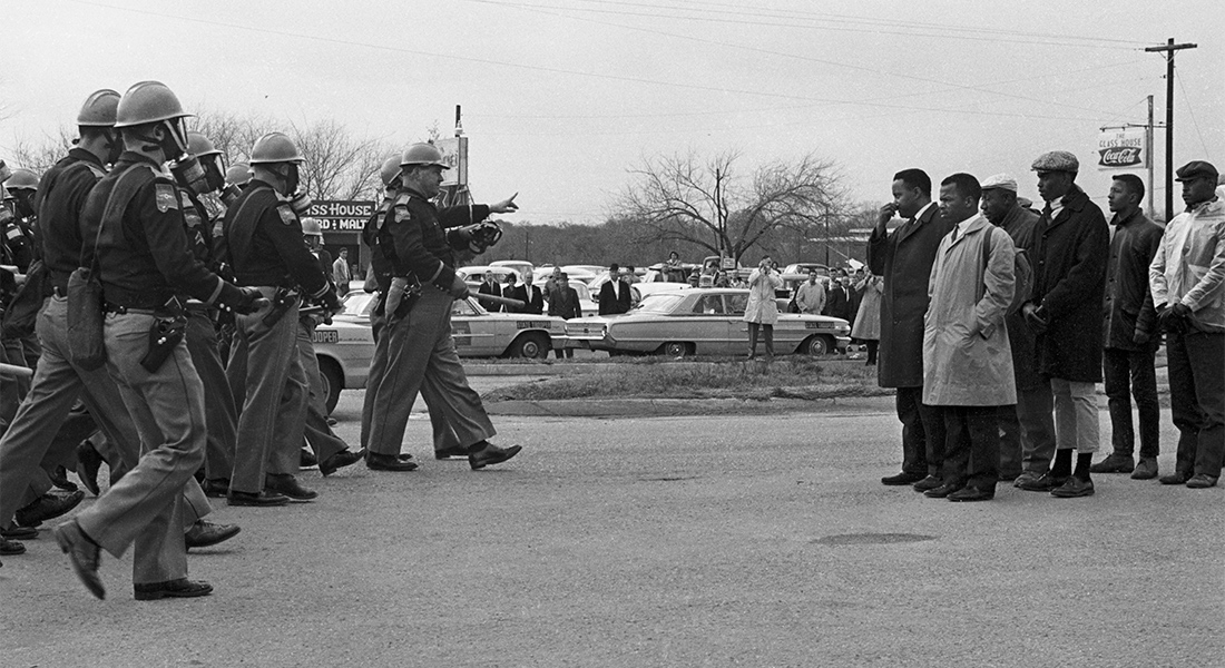 A black-and-white historical photo of Black protesters being confronted by police
