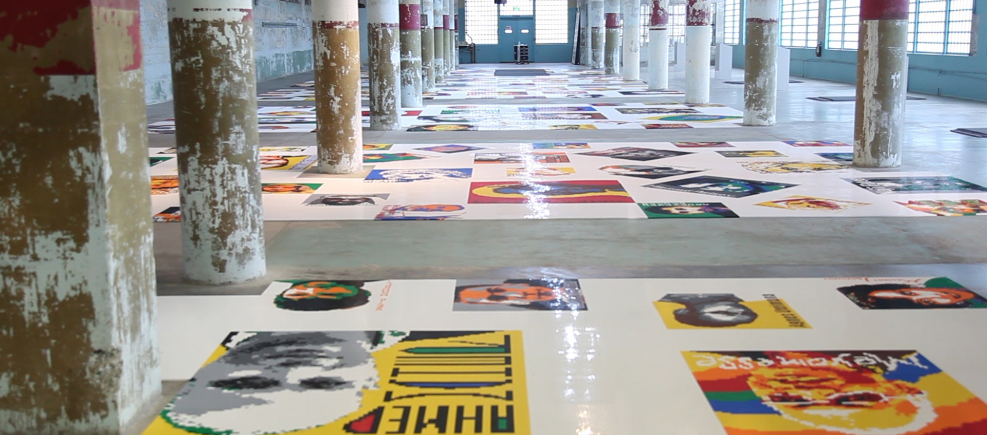 An installation view of Ai Weiwei's Trace, consisting of 190 portraits of dissidents made of Lego bricks arrayed flat on the floor of the former Alcatraz penitentiary